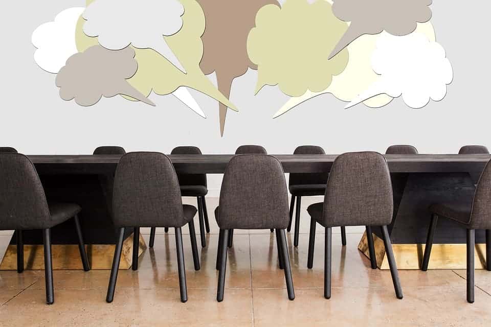 mesa de reunioes com baloes que representam pensamentos e fala