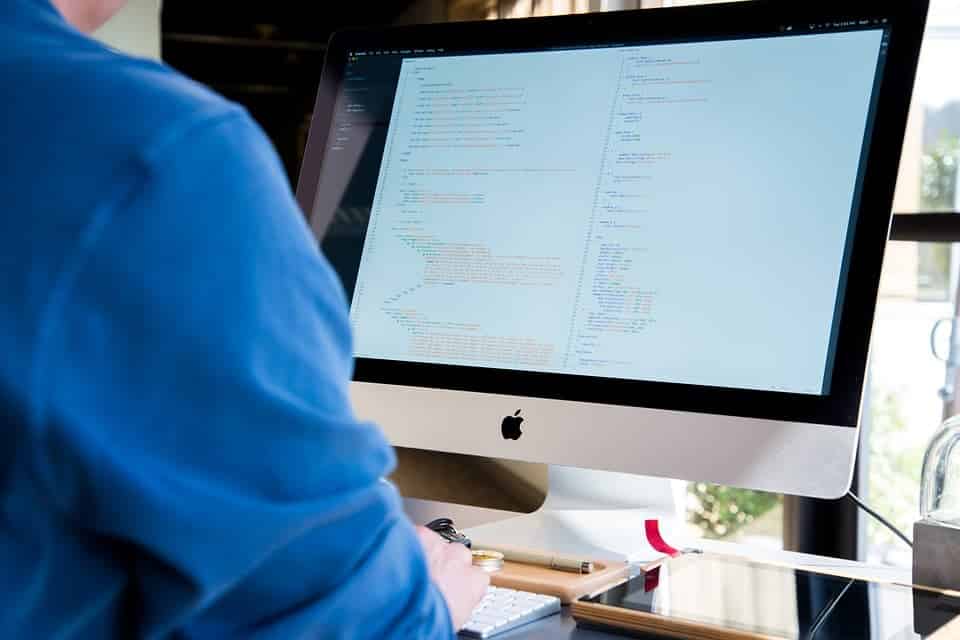 homem usando um computador com codigos de programacao na tela